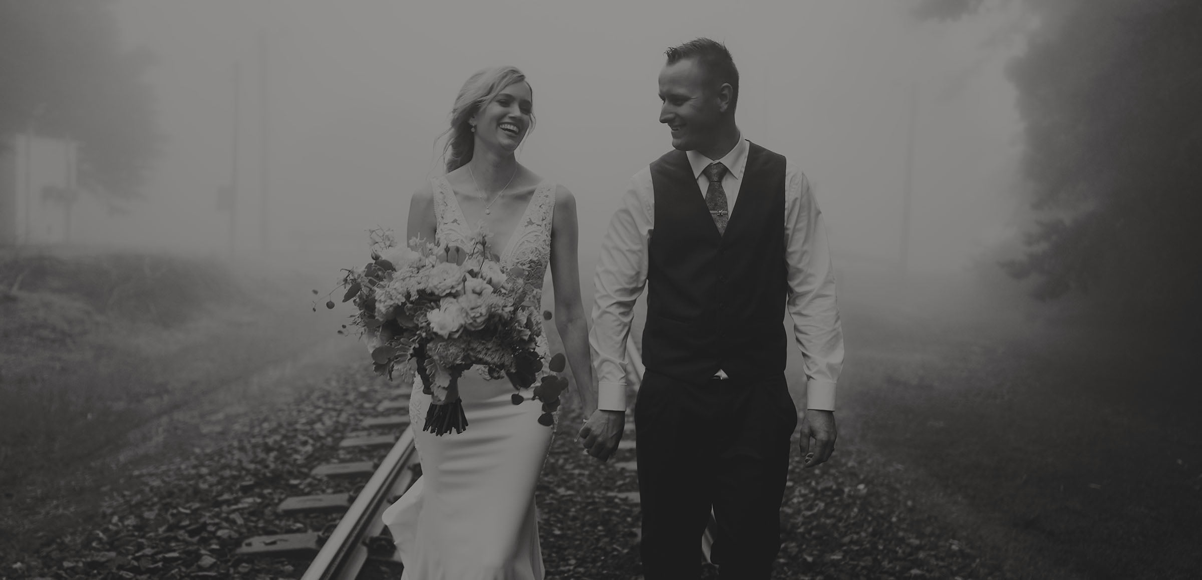 Bride and groom walk with wedding videographer black and white 2